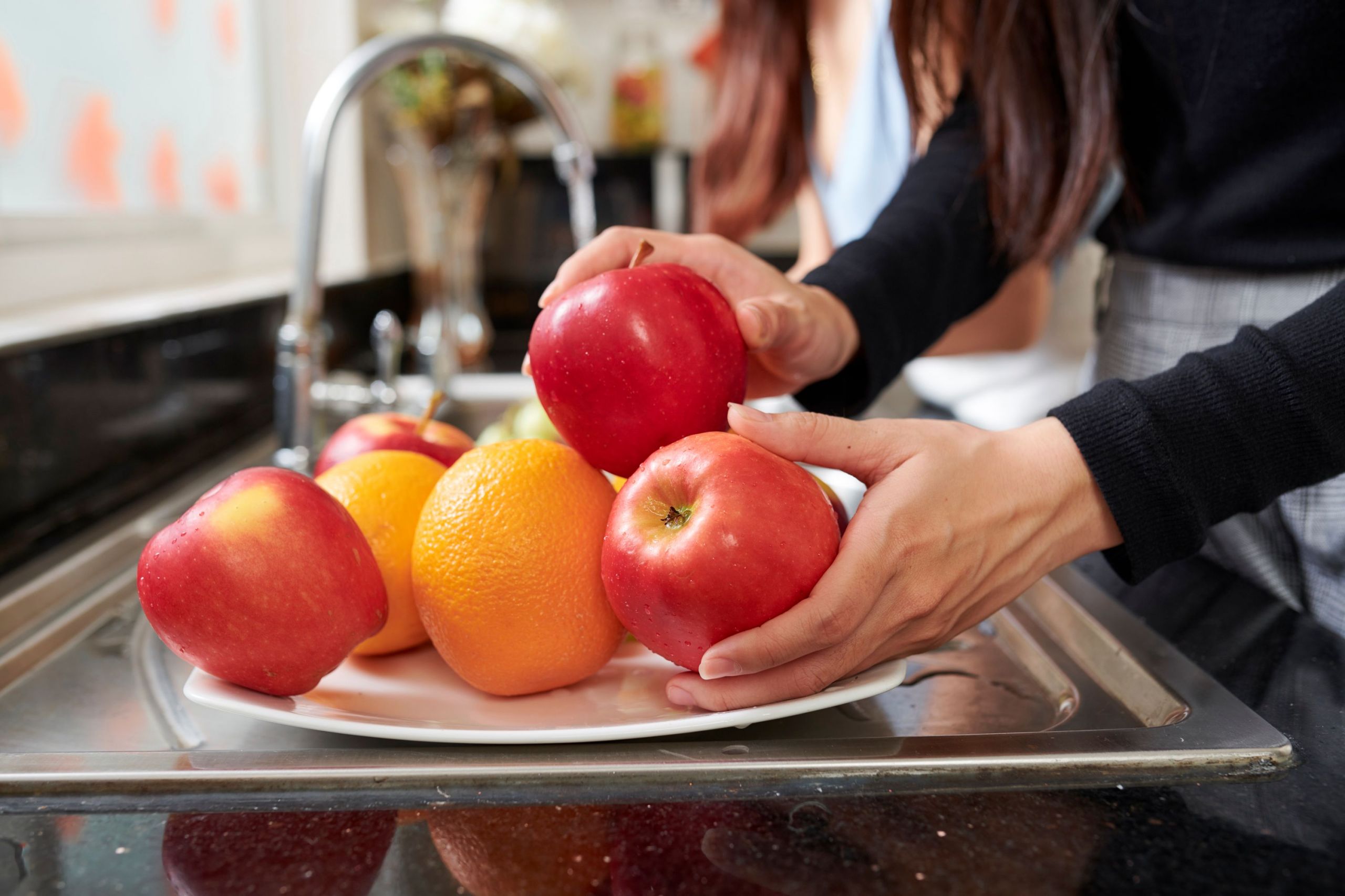 donna che lava frutta fresca per mangiarla dopocena