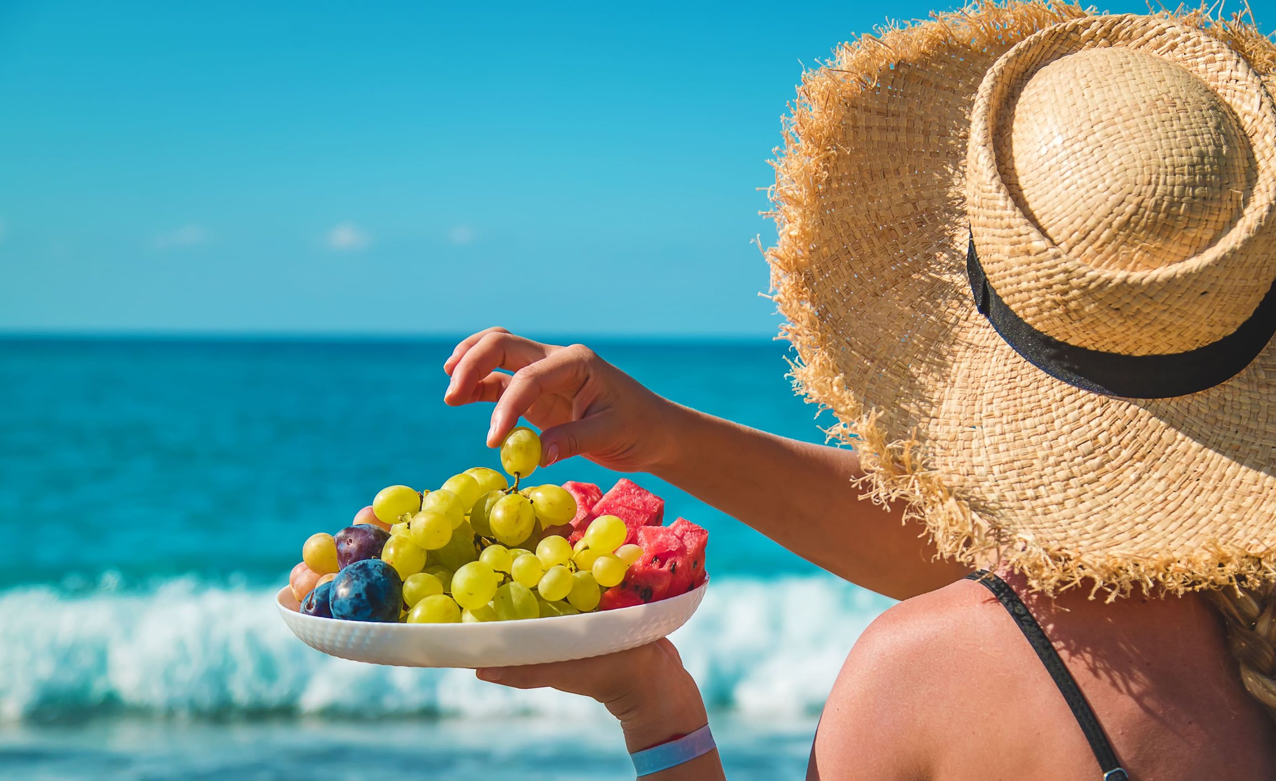 persona che mangia uva e altra frutta al mare