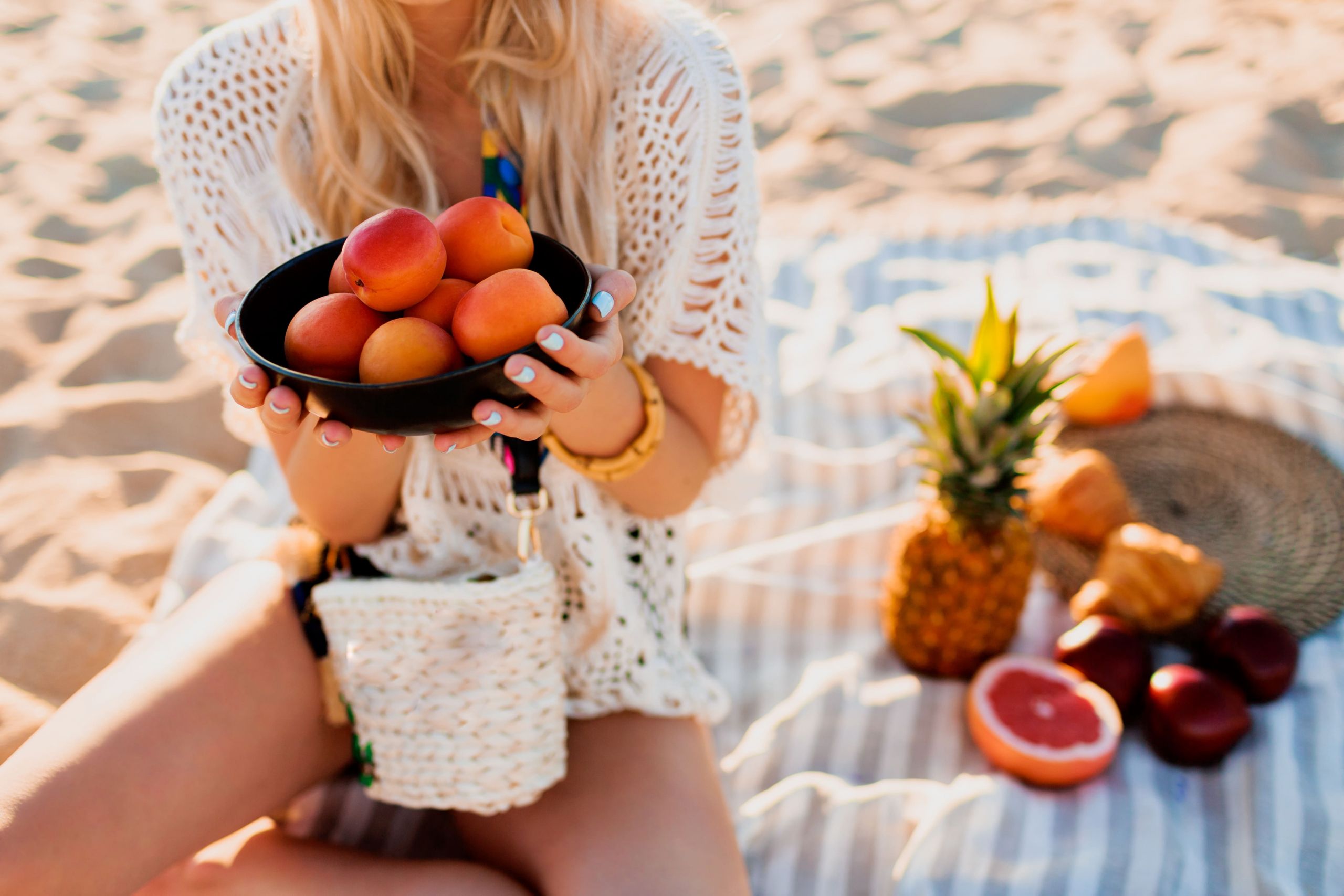ragazza che tiene della frutta in spiaggia
